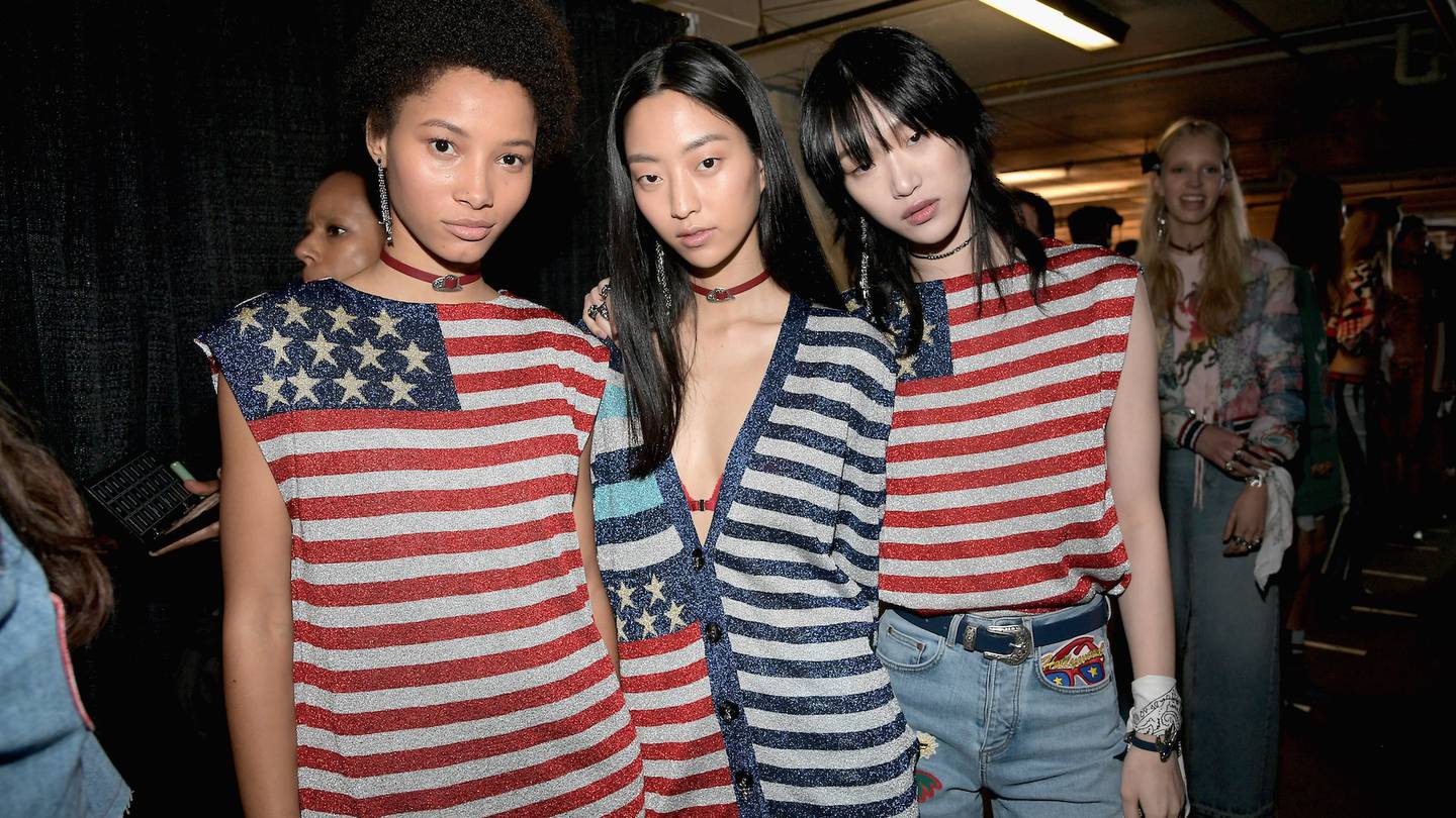 Models seen backstage at a Tommy Hilfiger show wearing clothes emblazoned with the American flag.