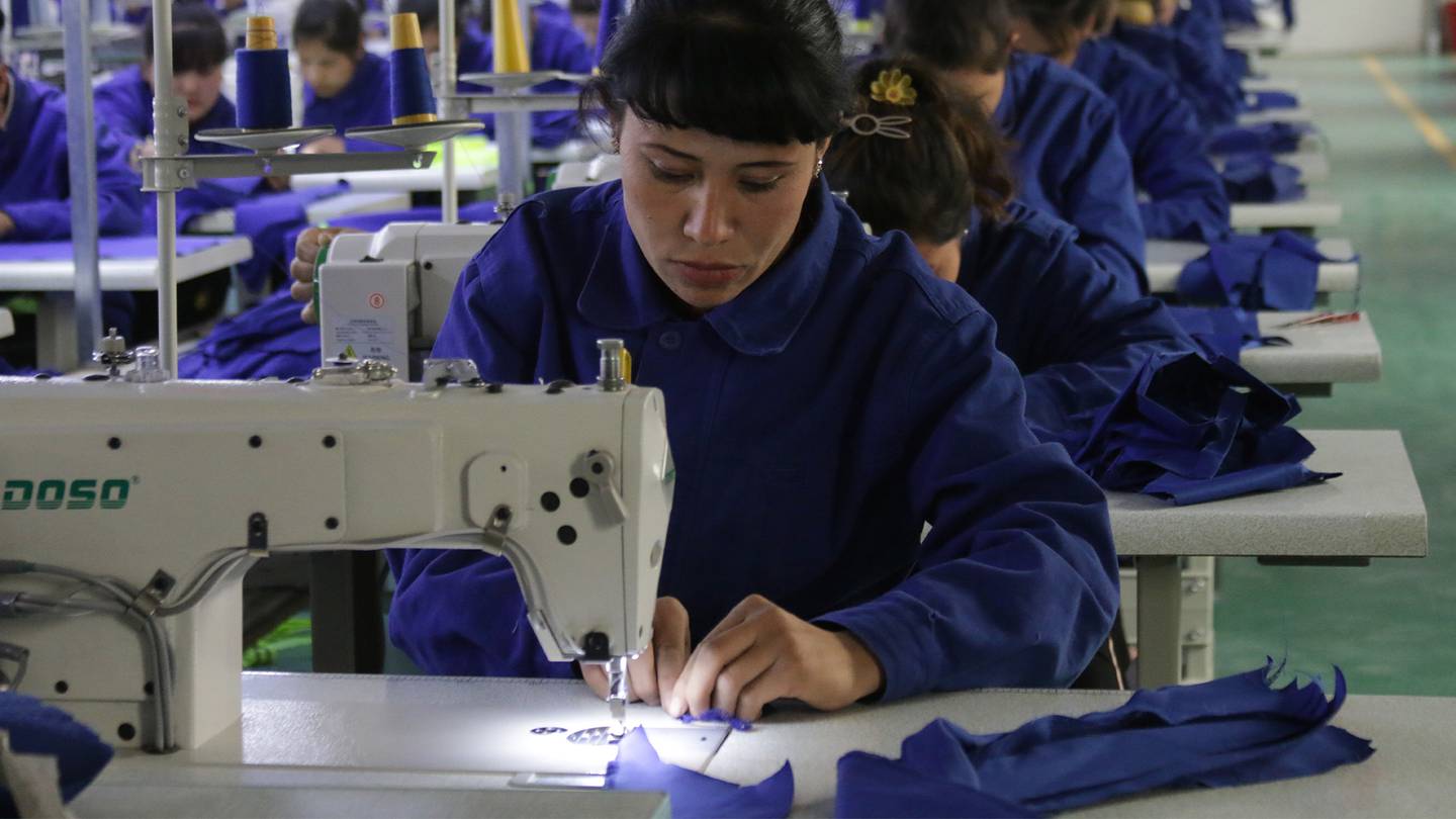 中国新疆和田县，一名妇女在一家工厂的缝纫机旁工作。