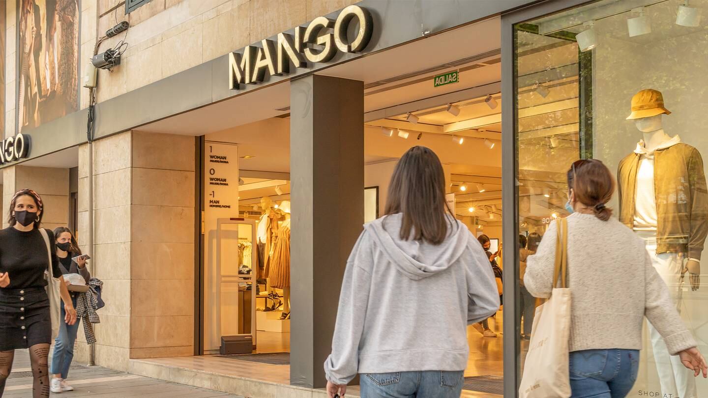 The front of a Mango store with customers walking past.