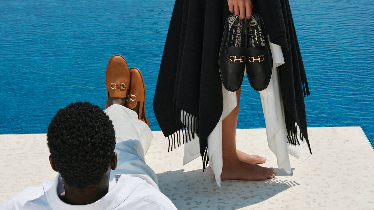 Models by a pool holding and wearing Salvatore Ferragamo shoes.