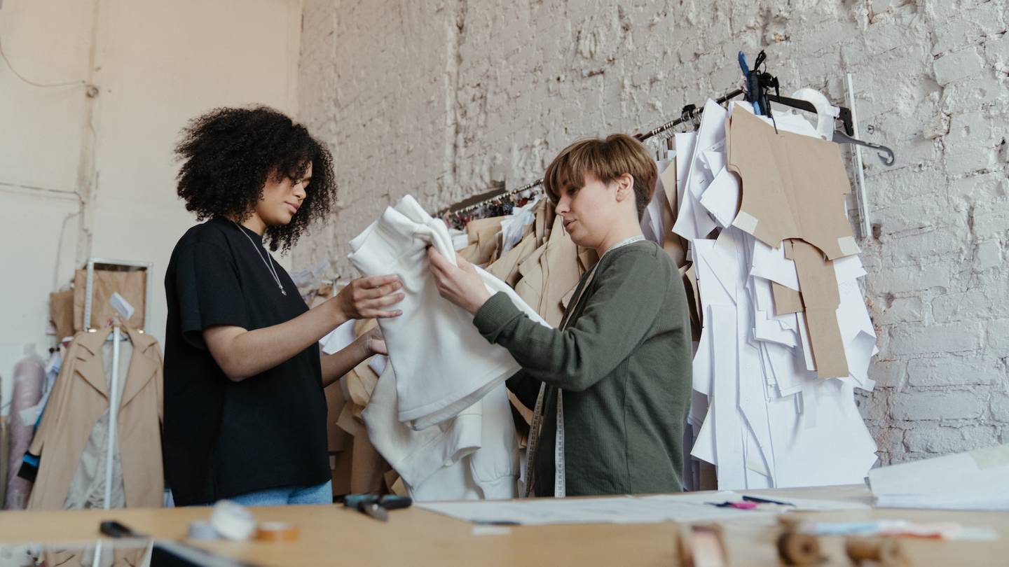 Two junior employees look at a garment in a design department