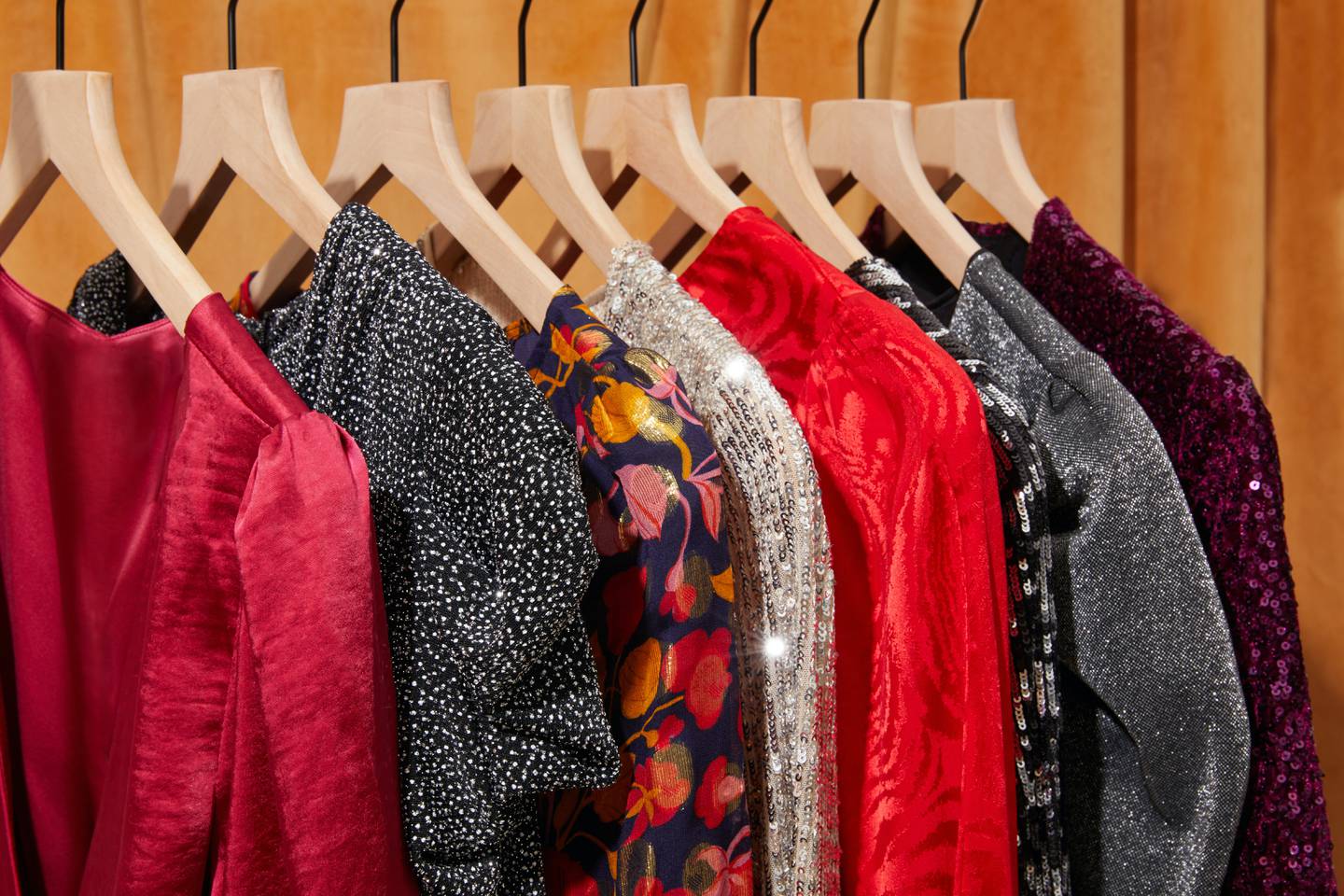 A rack of clothing, including red, floral pattern and sequin dresses.