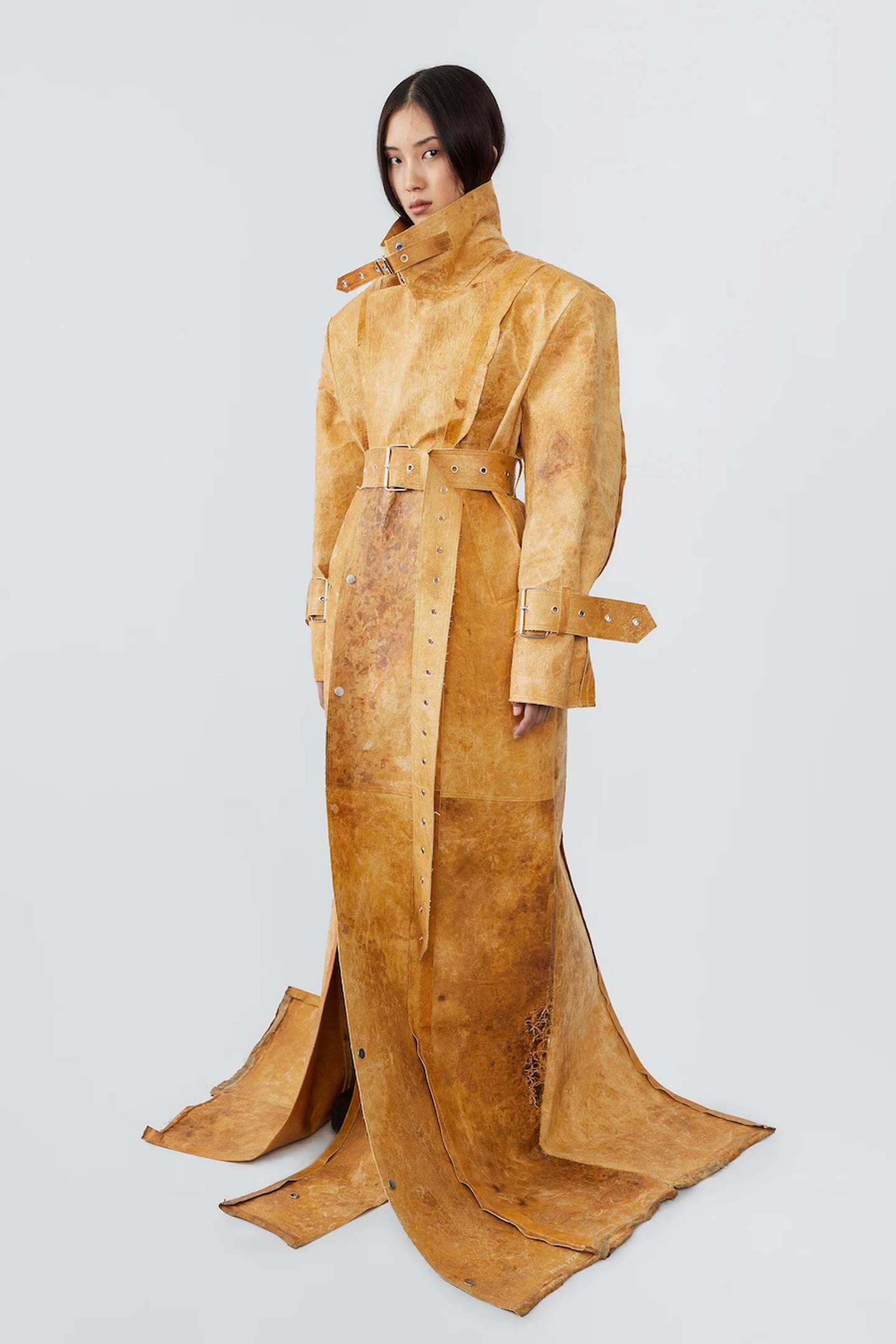 A woman glance sideways at the camera wearing a statement oversized trench coat made using MycoWorks' mycelium material as part of a capsule by Swedish brand Deadwood Studios.