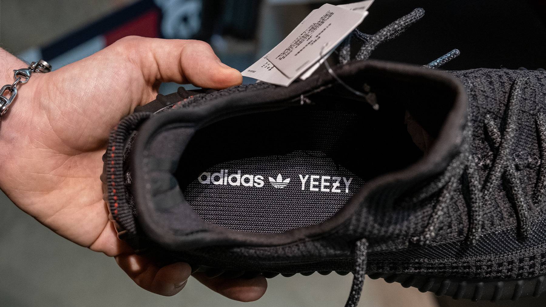 A reseller holds a Yeezy 350 sneaker to show the Adidas and Yeezy branding inside.