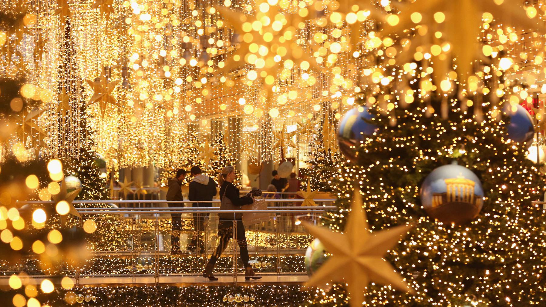 在德国柏林，购物者穿过一个购物中心，被圣诞装饰品点亮。盖蒂图片社。