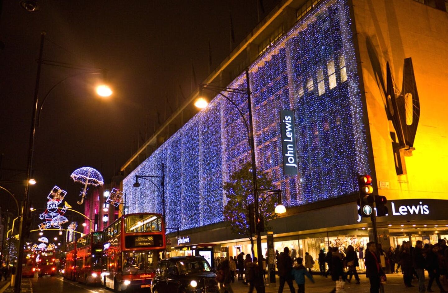 A John Lewis department store is lit up at night with holiday lights.