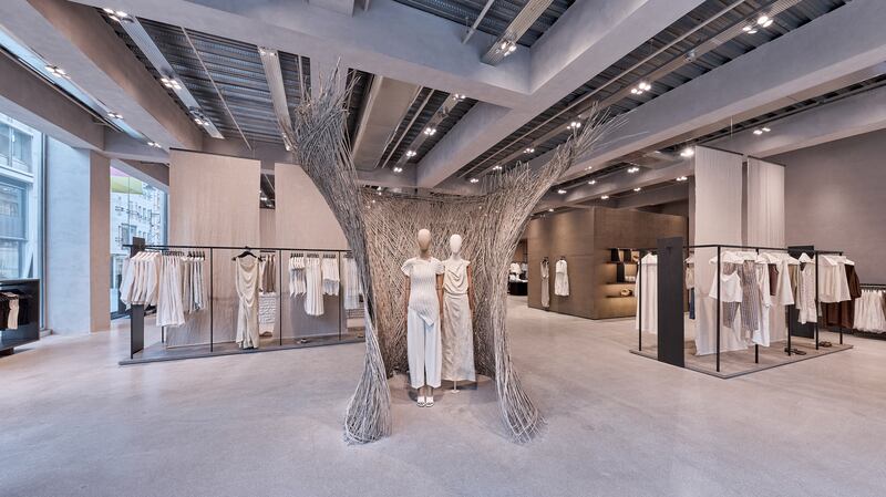 An open sales floor with lots of earth tones and and a wooden sculpture surrounding two mannequins.