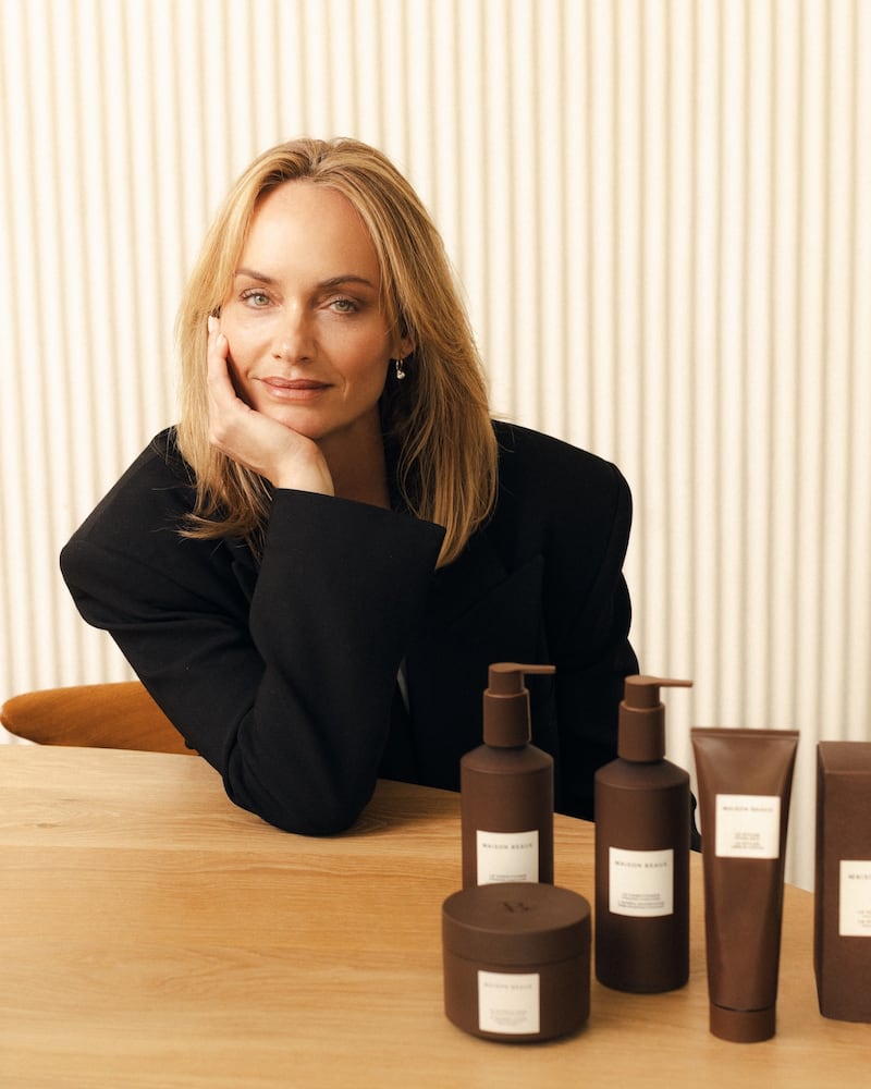 Amber Valletta sitting at a table with the five debut products from Maison Beaux