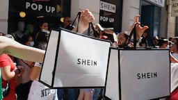 Shoppers hold up Shein bags outside a pop-up for the ultra-fast-fashion giant.
