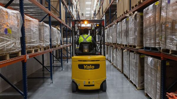 A worker operates a forklift to sort packaged goods destined for export, at a warehouse along the US-Mexico border.
