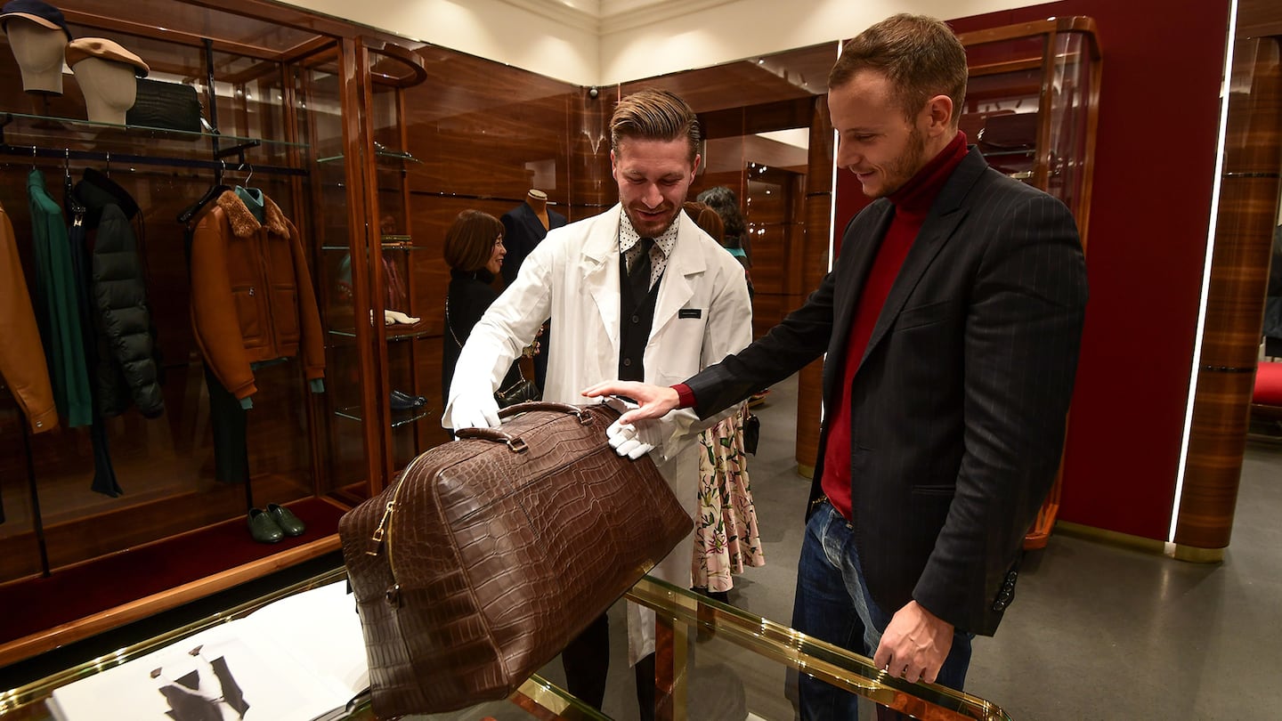 An employee shows a tan crocodile leather bag to a customer at a Dolce & Gabbana boutique.