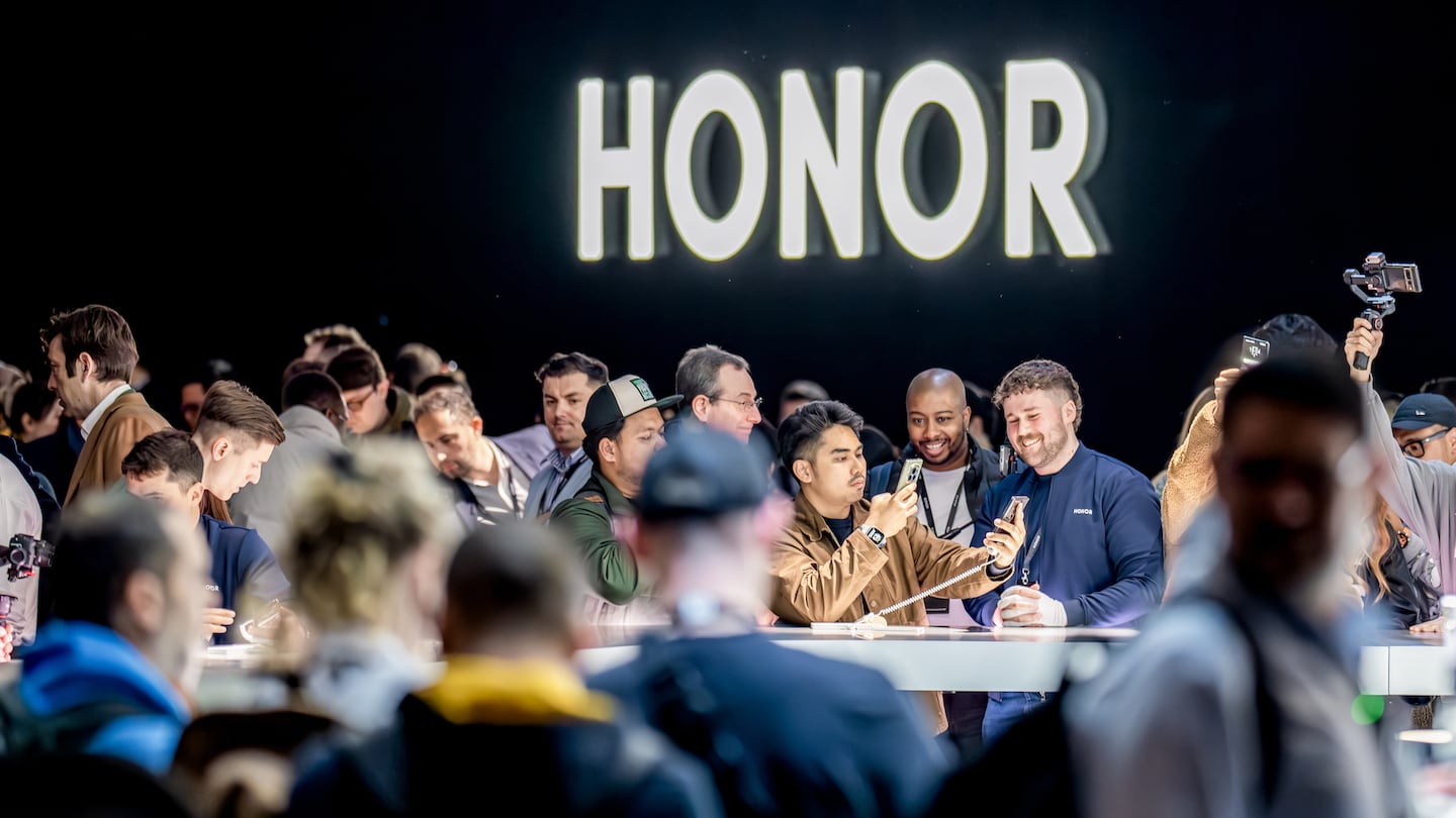 A crowd of people before the Honor logo play with smartphones.