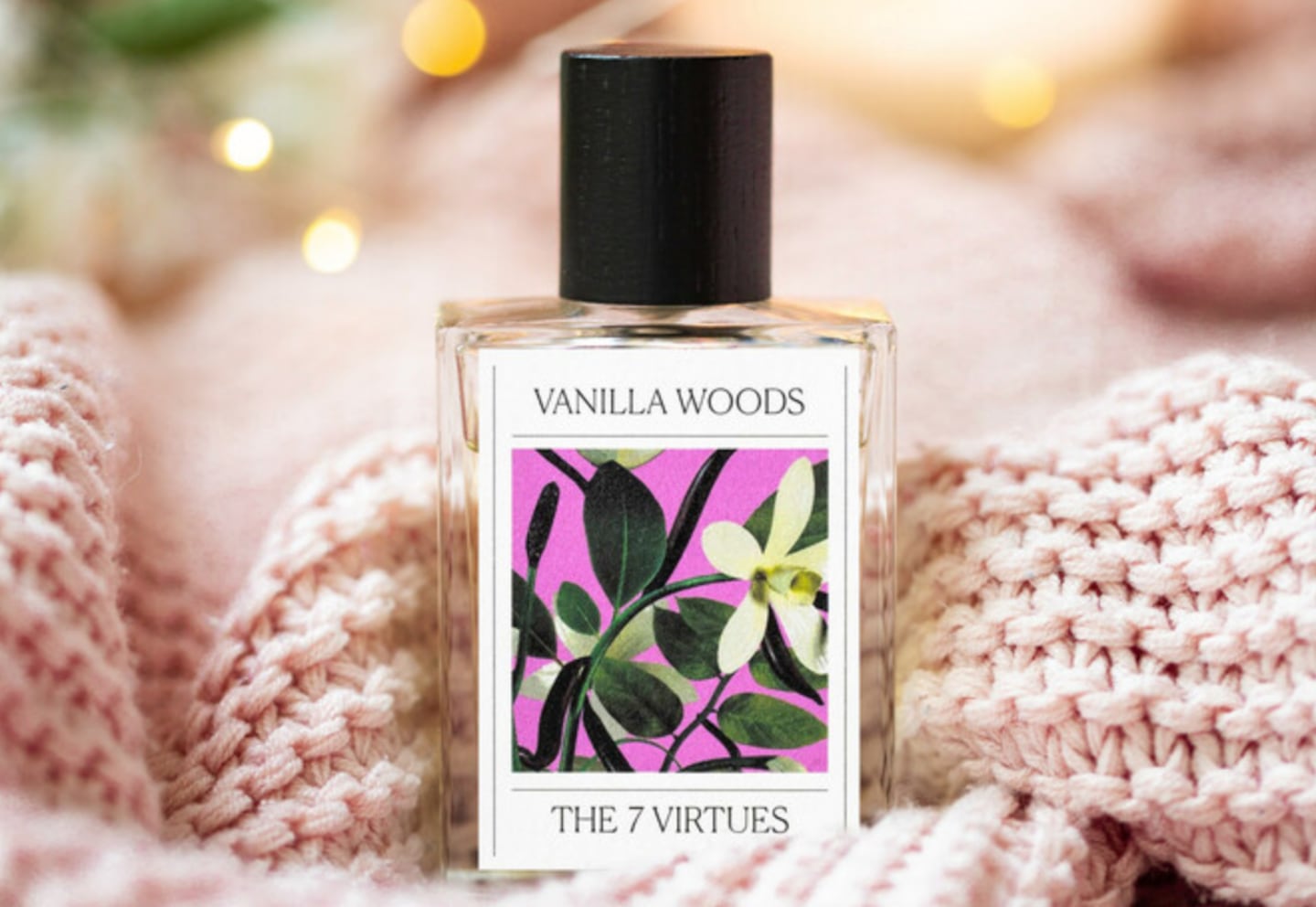 A bottle of perfume next to a pink knitted blanket.