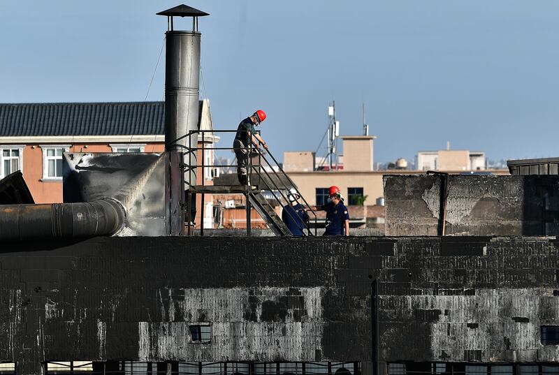 Investigators conduct an inspection on the roof of a shoe factory following a fatal fire on July 10, 2026 in Jinjiang, Fujian Province of China.