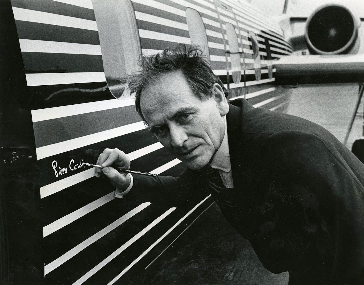 Italian-born French fashion designer Pierre Cardin signs his name on the outside of his plane in Washington, DC on September 11, 1978. Ellsworth Davis for the Washington Post. Getty Images.