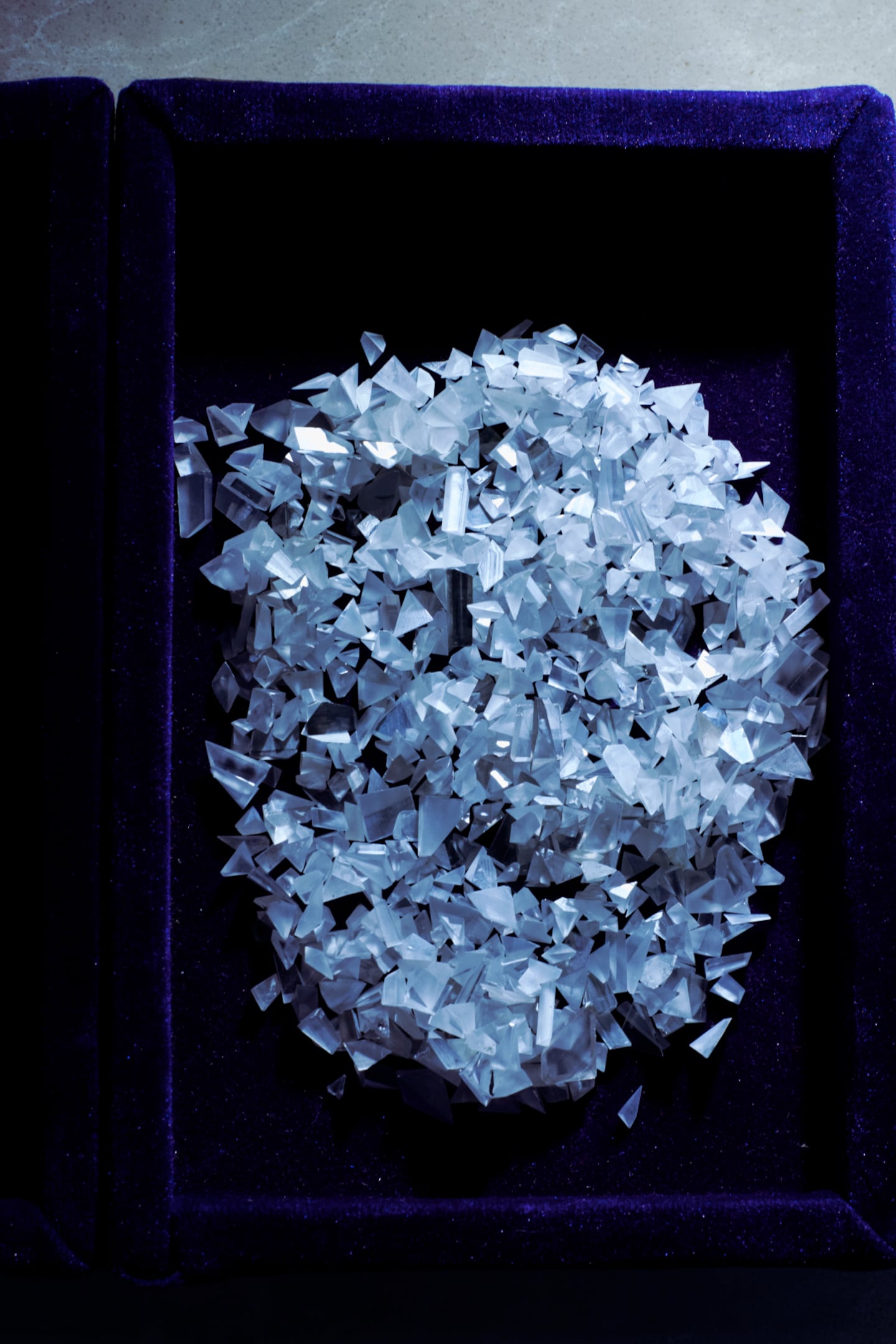 A pile of rough diamonds sits in a container lined in dark velvet.