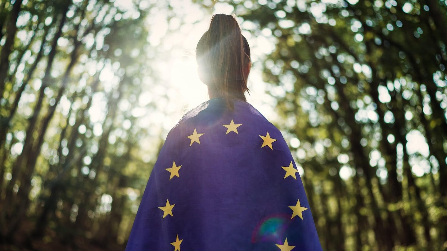 A girl wears a European flag like a cape.