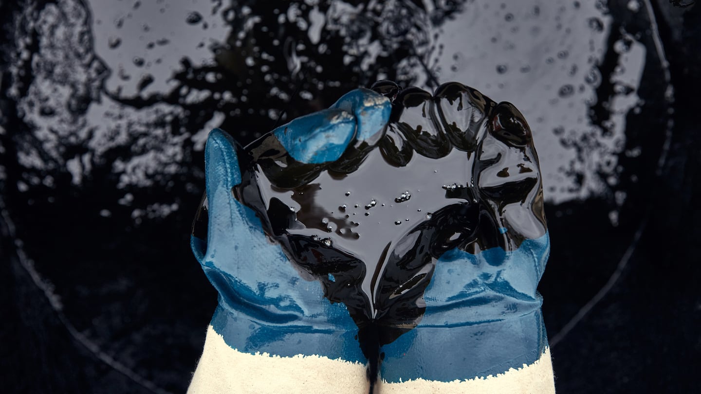 A pair of rubber gloves is soaked in crude oil.