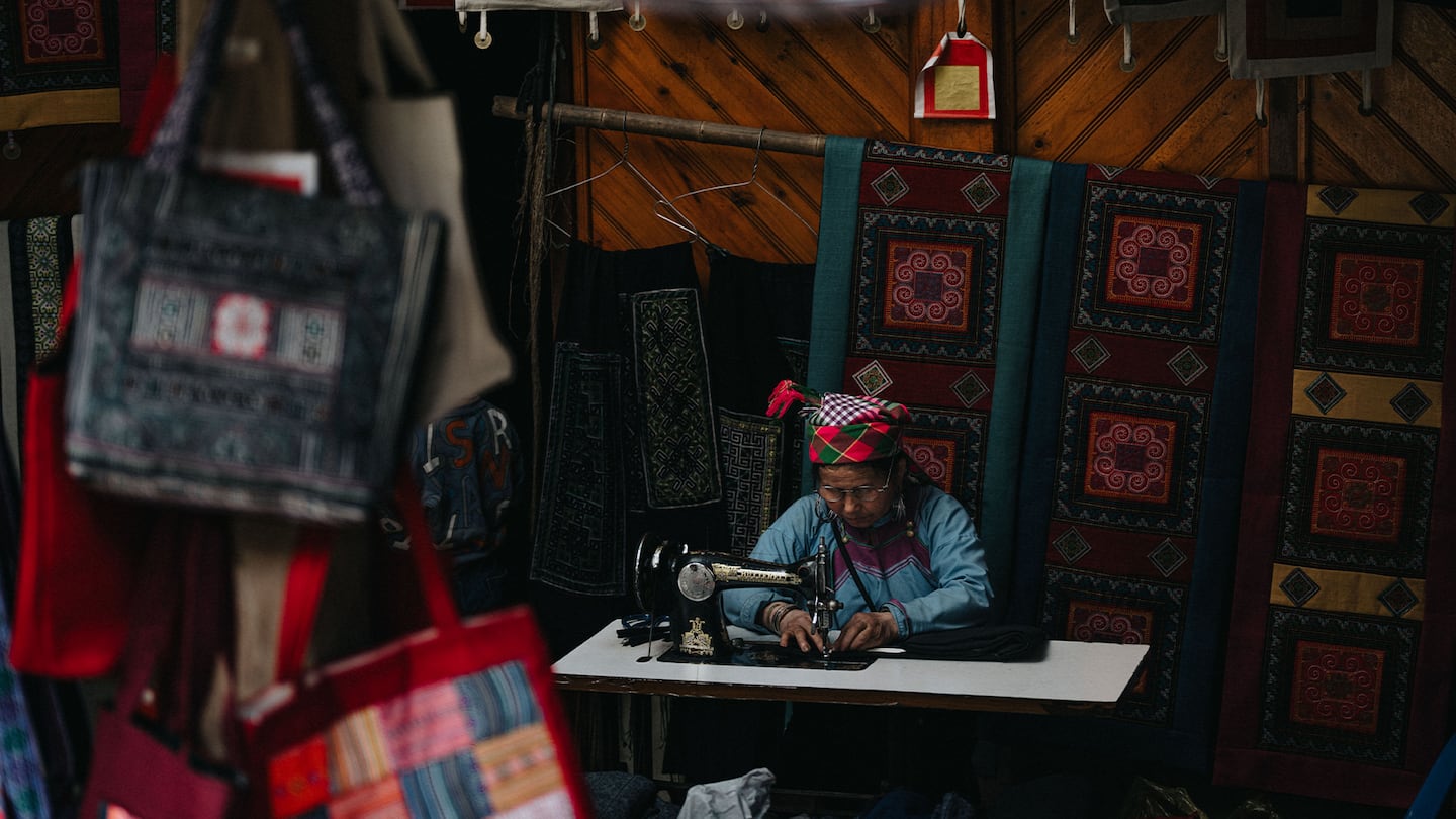 A vibrant scene of a traditional textile market in Lào Cai, showcasing handcrafted fabric and bags.