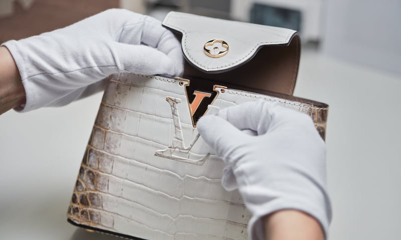 A worker in a Louis Vuitton workshop in Loir-et-Cher attaches the brand's logo to an exotic leather bag.