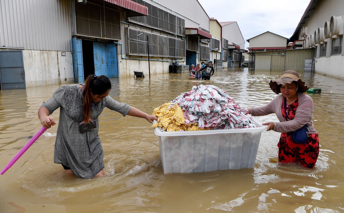 Workers salvage clothes from a factory through floodwaters on the outskirts of Phnom Penh in 2020.