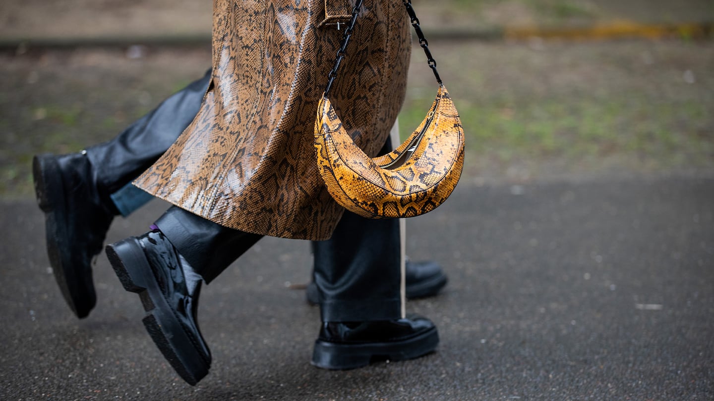 A guest is seen wearing coat and bag with snake print outside Rodebjer during Copenhagen Fashion Week.
