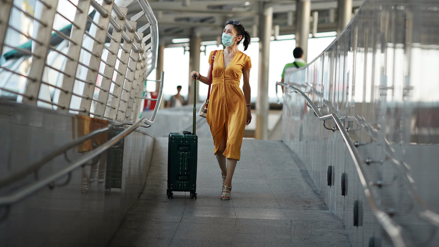 A woman walking with luggage at a railroad station.