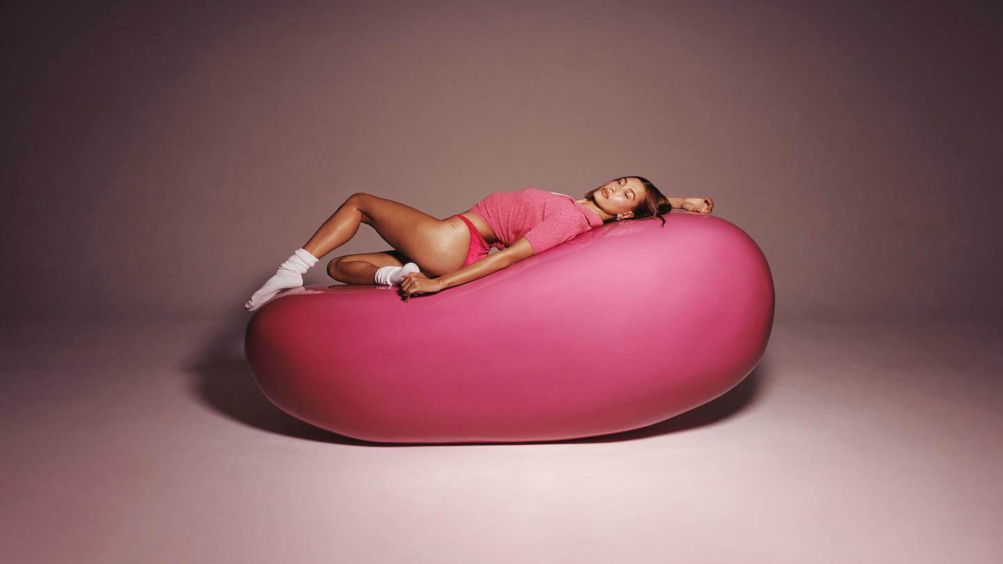 A woman lying on a life size jellybean.