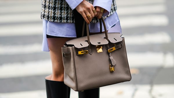 A person wears a beige leather Hermes Birkin bag, finger rings, outside Hermes, during Paris Fashion Week