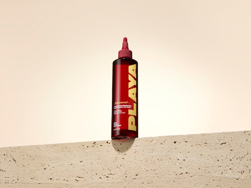 Playa's first product, the Fragrance-Depositing Gloss Rinse for Hair, with a red bottle and bold yellow logo.
