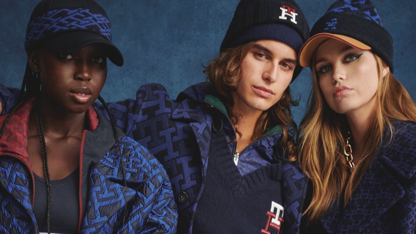 Three models wearing Tommy Hilfiger-branded outfits post against a blue backdrop.
