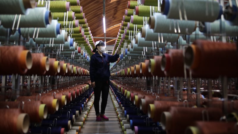 A worker inspects spools of recycled polyester thread.