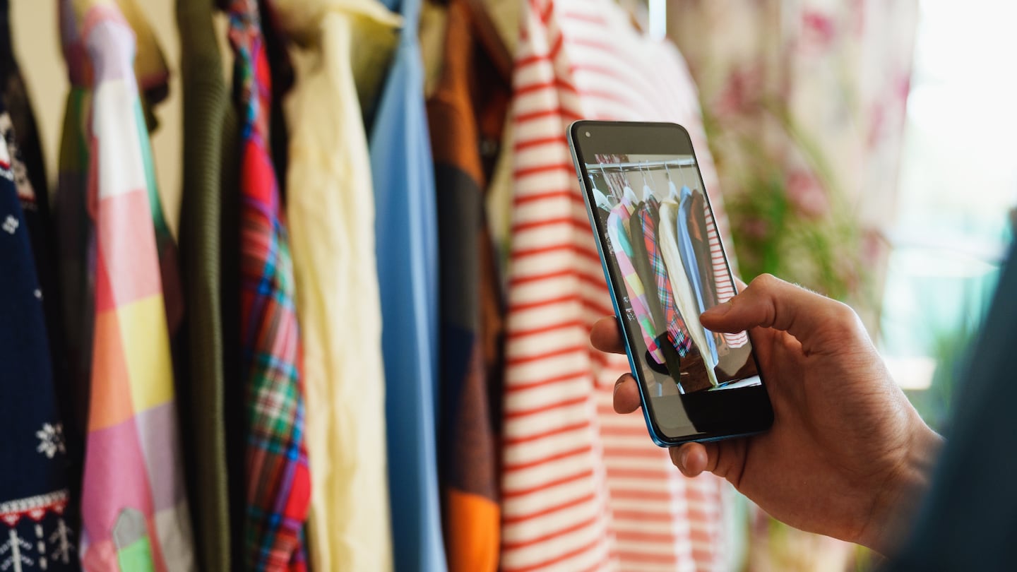 An image shows a person taking a picture of clothing hanging in their closet.