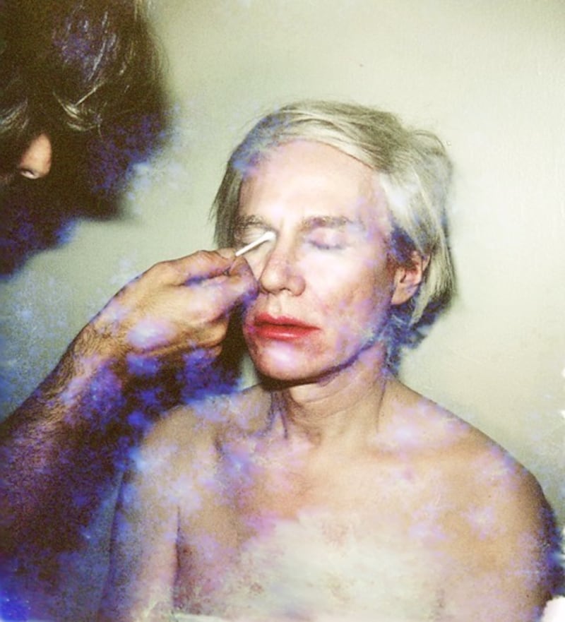 An exclusive unseen image of Andy Warhol from the archive of Ronnie Cutrone depicting Warhol in the process of having drag makeup either applied or removed.