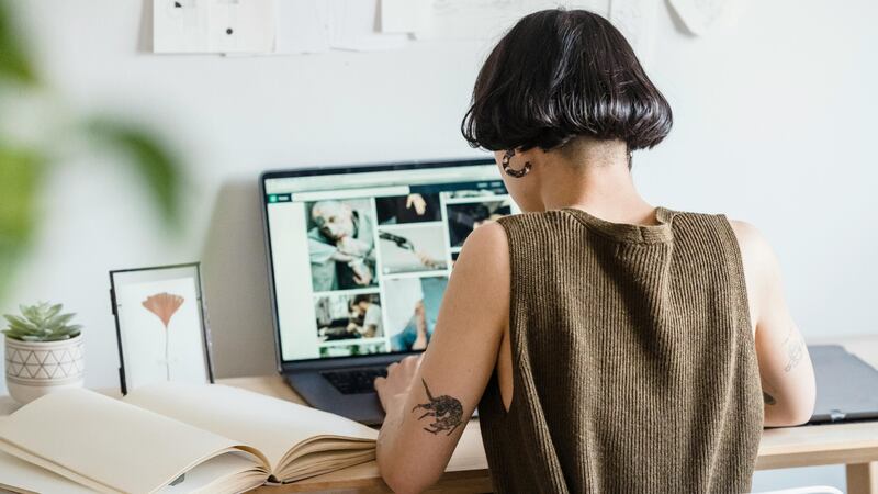 A young creative designer working remotely at her desk with sketches and a laptop.
