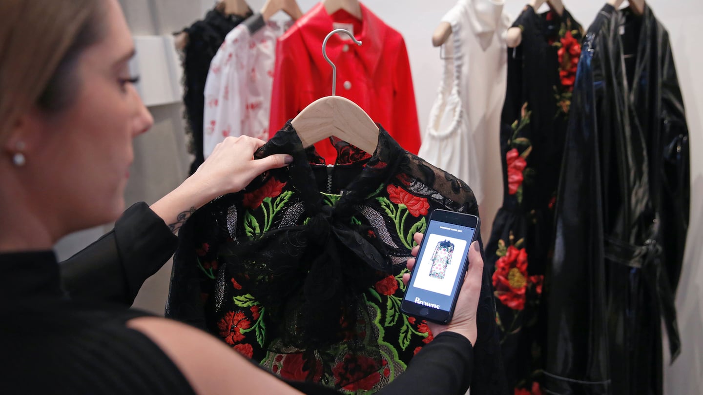 A Farfetch employee uses an app linked to store products at the launch of the "Store of the Future" exhibition at the Design Museum in London