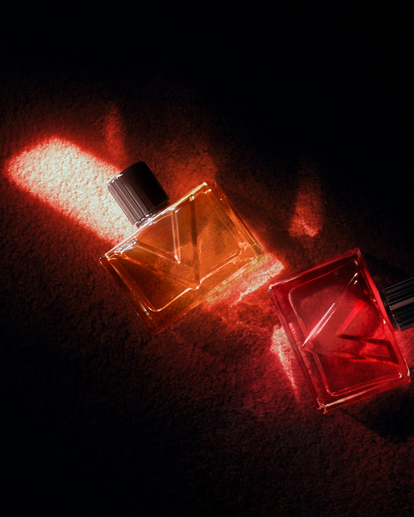 Valentino Beauty Vendetta bottles for him and her. Each bottle is square with an embossed V. One is orange, and the other is red.