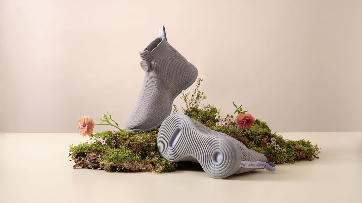 Two sock-like Mo.onshot sneakers arranged on a mossy bed.