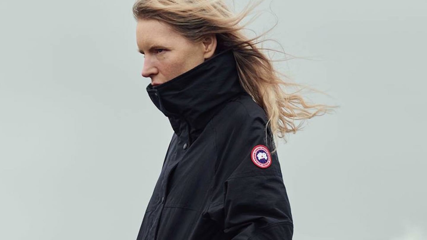Model wears a Canada Goose black coat with the logo on the sleeve.