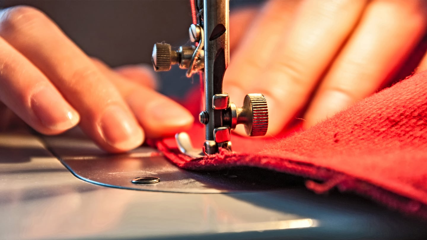 Person at a sewing machine putting through red material.