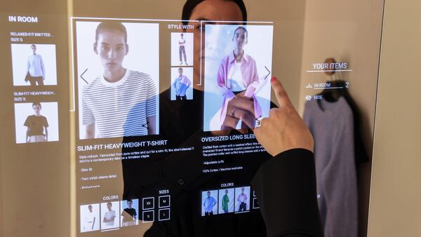 A woman looks at images of a product displayed on a mirror showing product information, styling suggestions and more.
