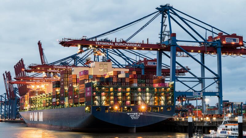 Container ship at Hamburg Terminal Burchardkai with cranes at twilight.