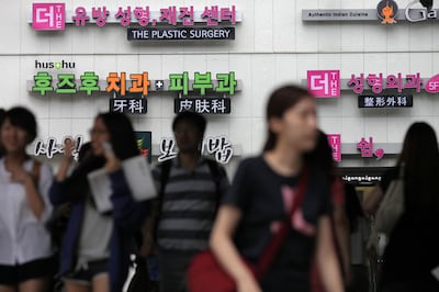 Signs for plastic surgery clinics are displayed on a building in the Apgujeong-dong area of Gangnam district in Seoul. Woohae Cho/Bloomberg via Getty Images.