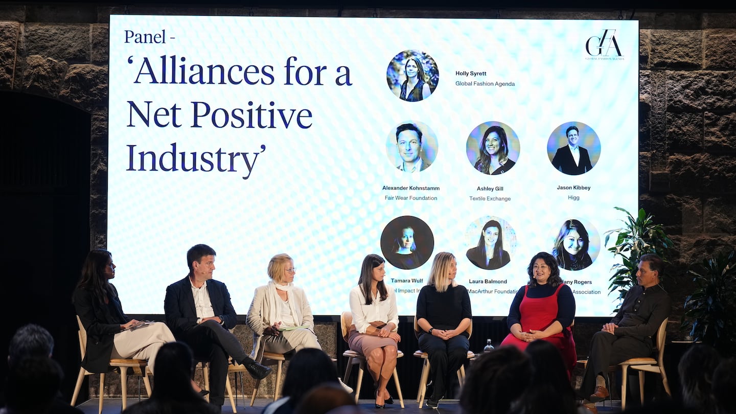 A panel discussion takes place against a screen that reads "Alliances for a Net Positive Industry" at the Global Fashion Agenda's annual Copenhagen Fashion Summit.