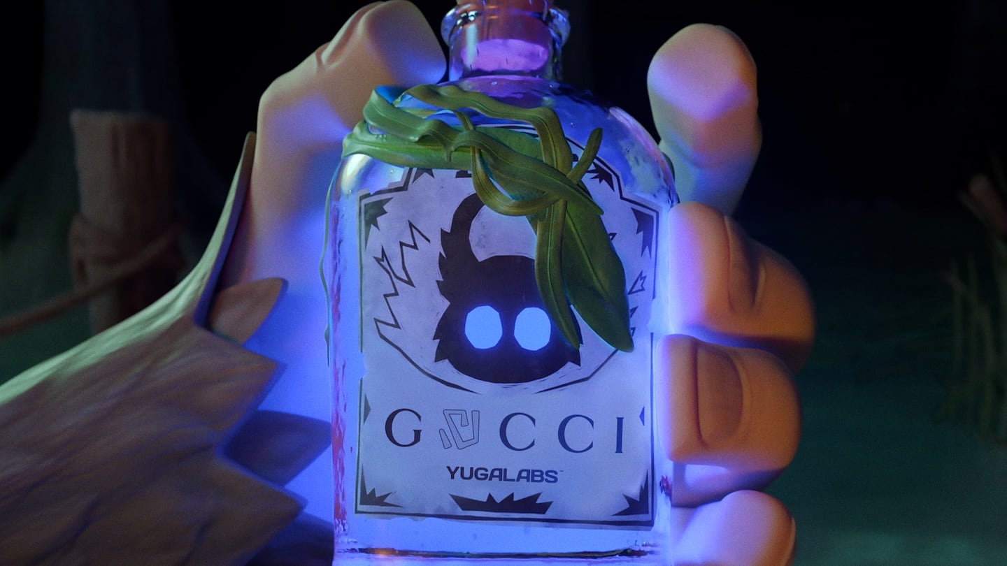 A digital ape hand holds a small bottle bearing the Gucci logo.