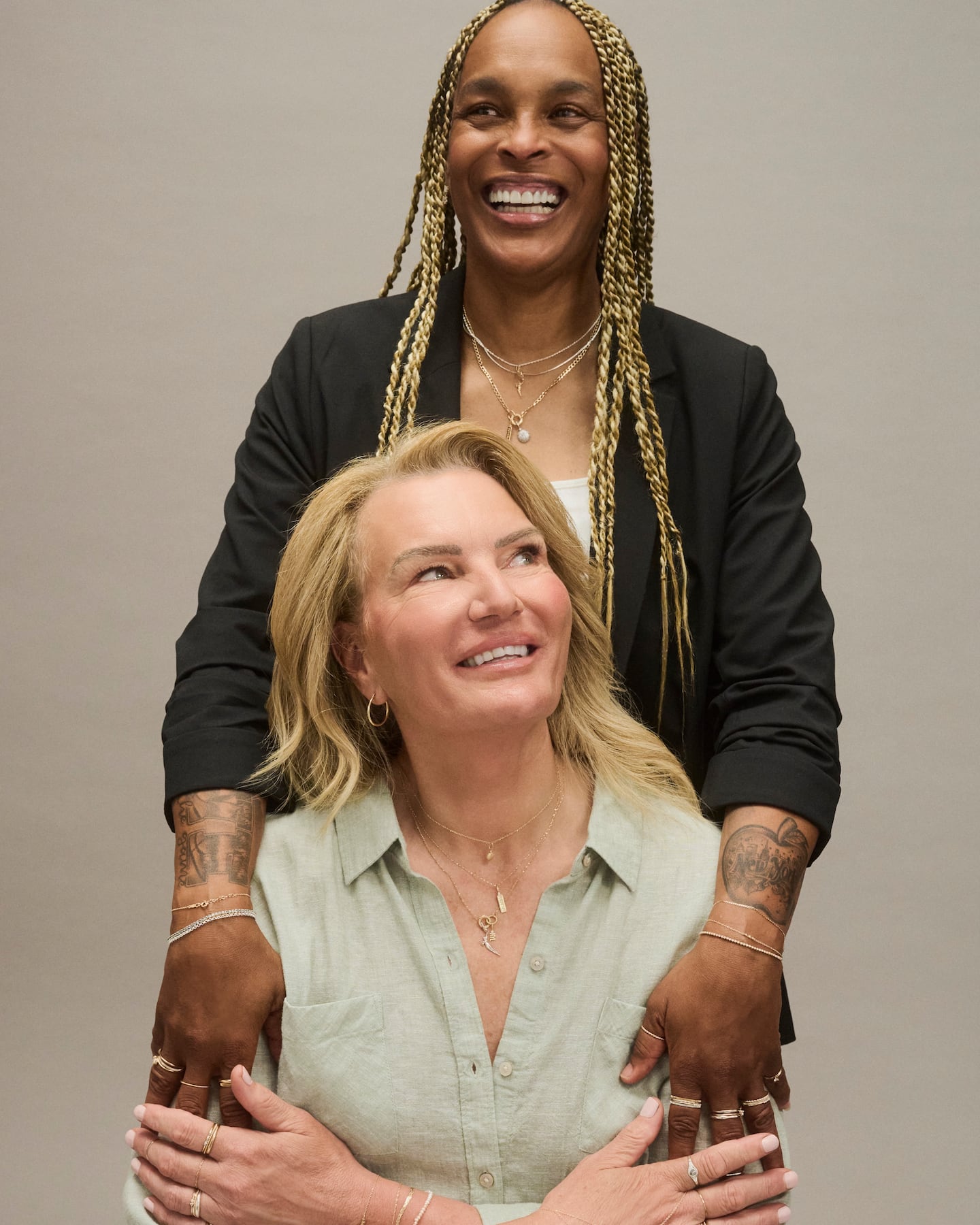 Teresa Weatherspoon stands over Sue Wicks and puts her hands on her shoulders. Both are wearing jewellery on their hands, necks and wrists featuring Catbird's new WNBA charms.