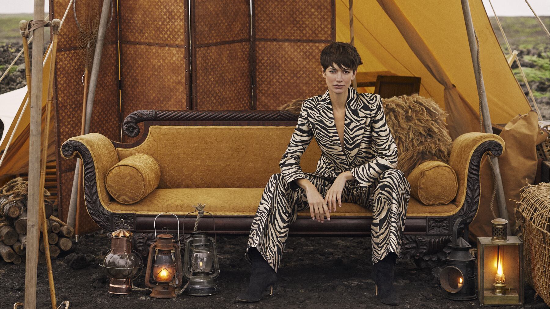 Woman in a zebra suit sitting on a yellow couch in yellow tent.