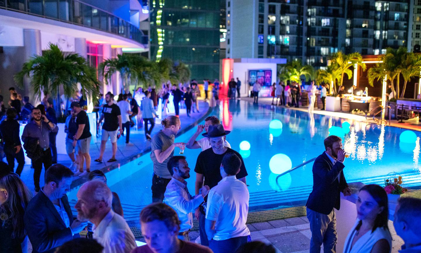 Guests talk around a pool at a swanky venue in Miami.