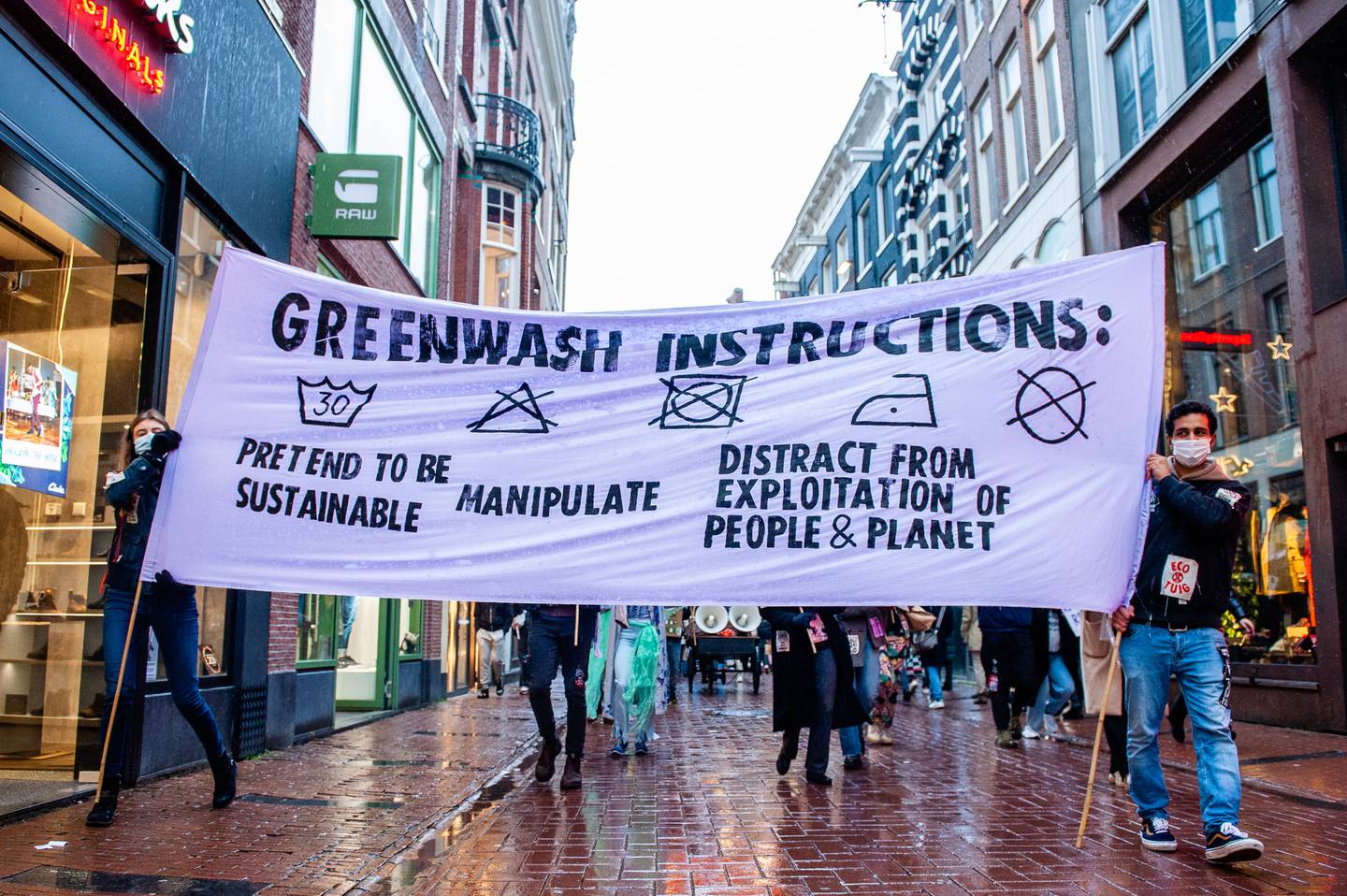 XR activists hold a banner showing a clothing care label with the headline "Greenwash Instructions" during a protest in Amsterdam in 2021.