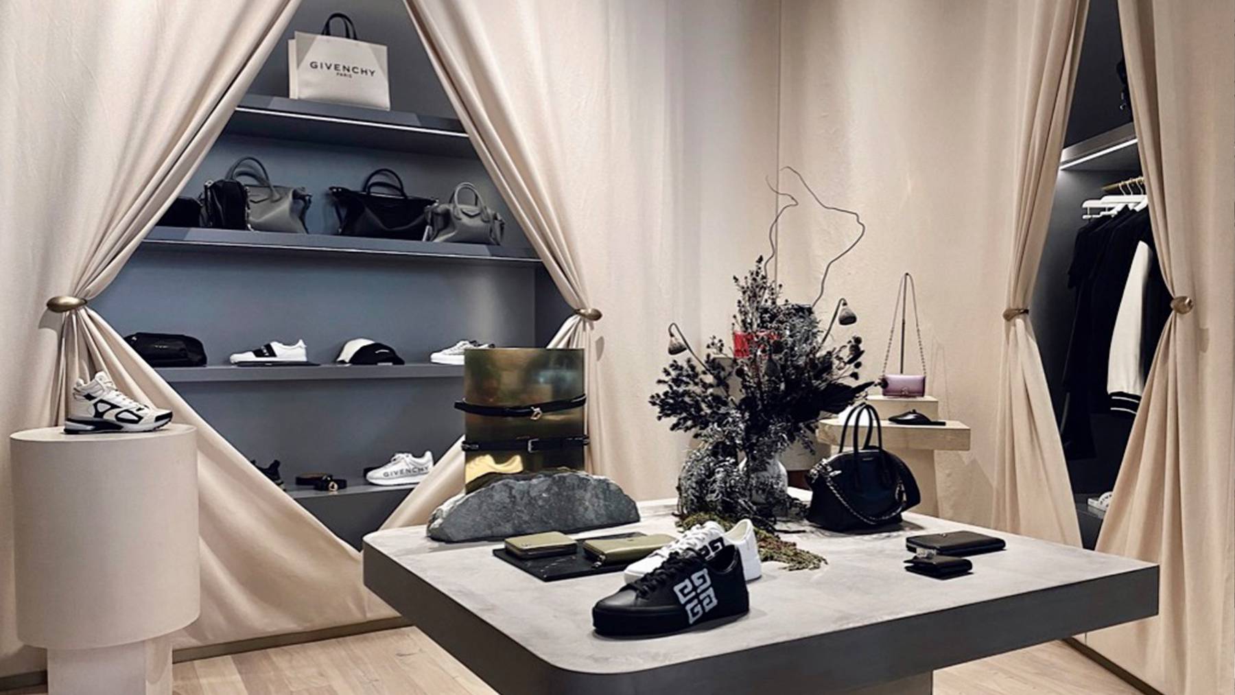 Inside the Faradays store, products sit on a stone table in the centre of a white draped room. Shelves with more products including bags, shoes and other accessories sit at the back behind the table.